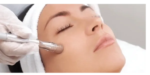 Woman receiving a facial treatment with a metal tool.
