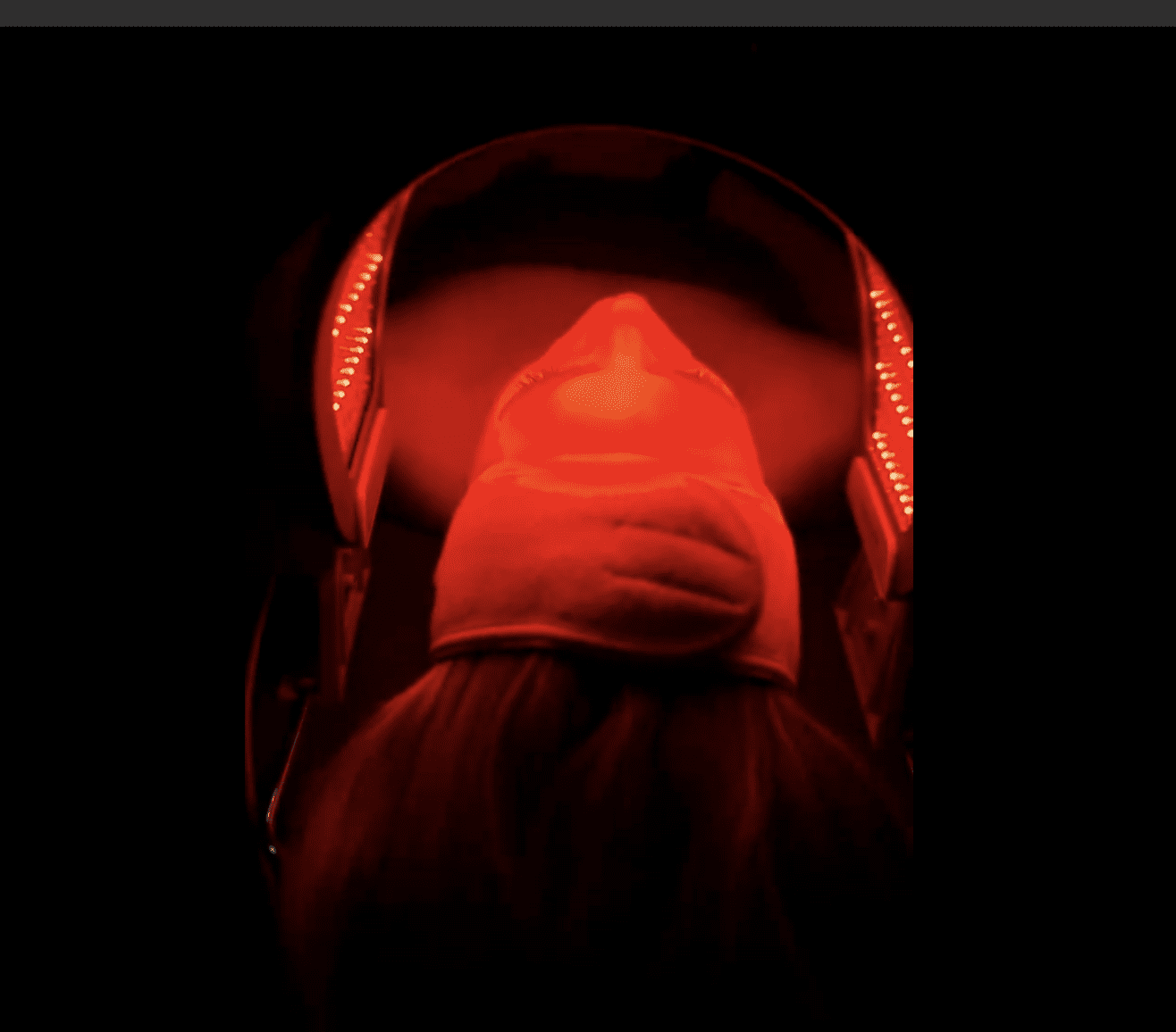 Person illuminated by red light, looking downwards.