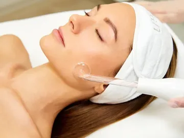 Woman enjoying a relaxing facial treatment with a beauty device.