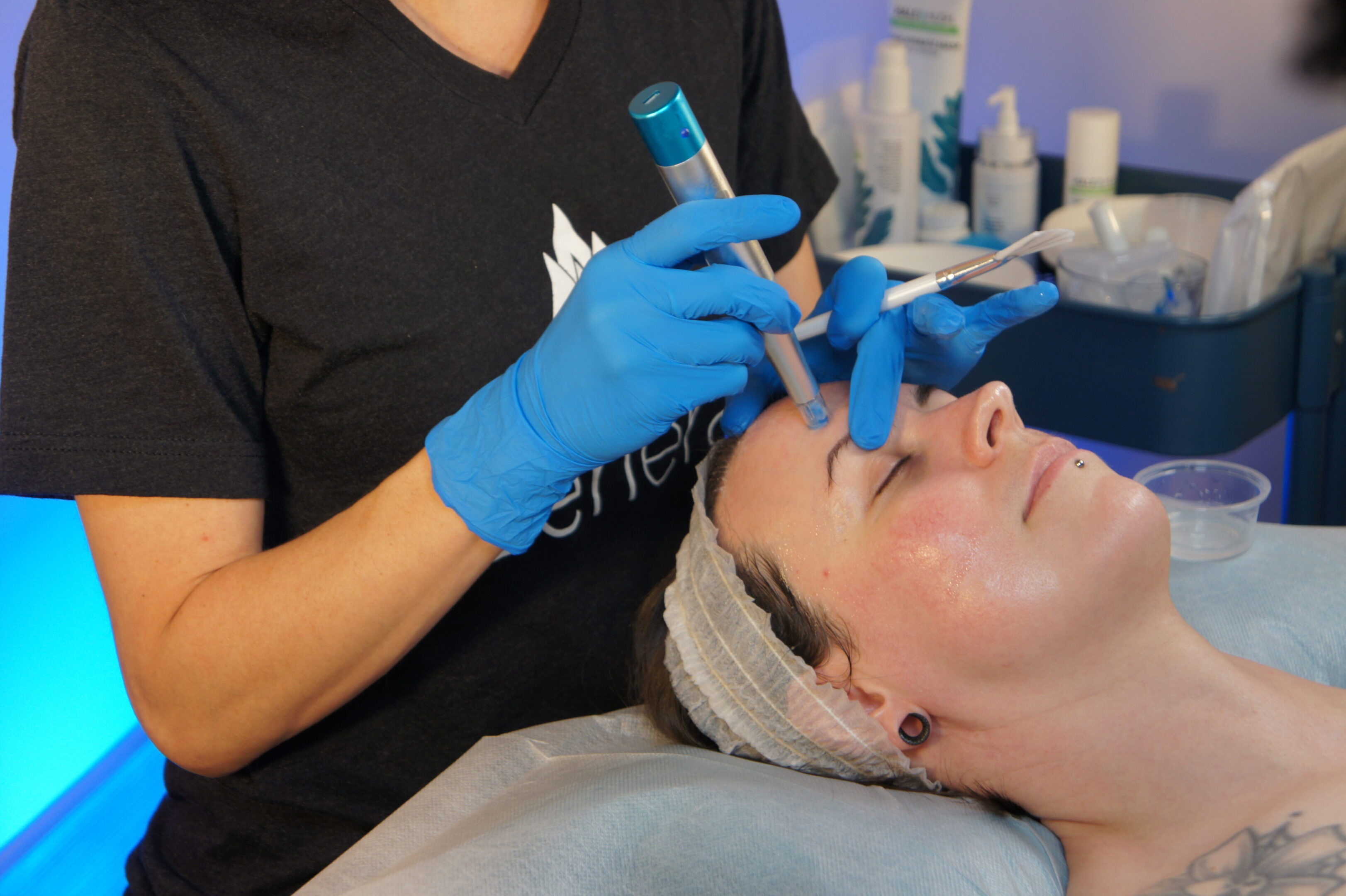 A professional performing a facial treatment with a handheld device.