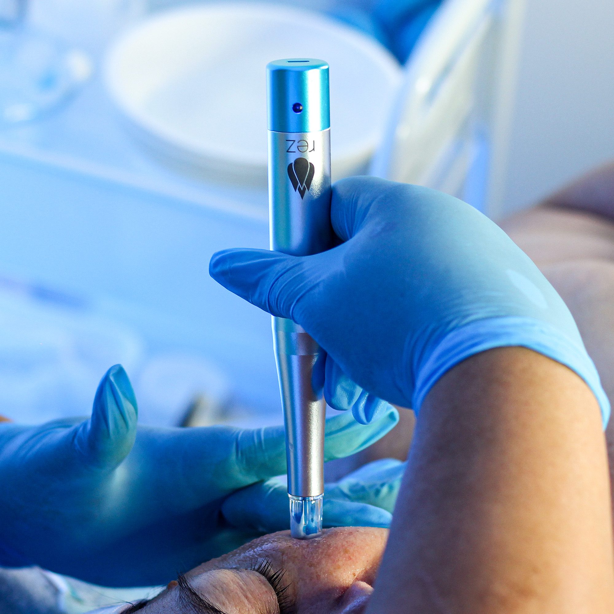 A medical professional using a handheld device on a patient's arm.