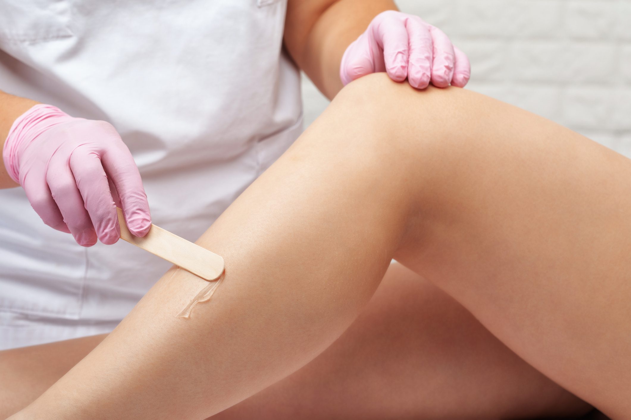A person applying wax to leg hair for hair removal.