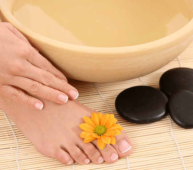Relaxing foot bath setup with woman showing her nails for her hands and feet