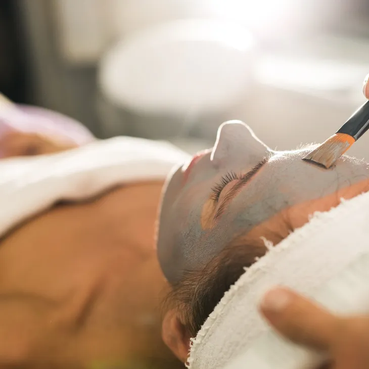 Person receiving a facial spa treatment with a brush.
